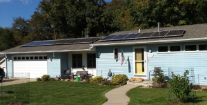 A ranch style home with a solar array on the house, and one on the garage
