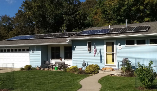 A ranch style home with a solar array on the house, and one on the garage